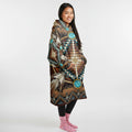 Side profile of a woman wearing a brown tribal blanket hoodie with turquoise medallion designs, hands in pockets, showing the hood and side panel