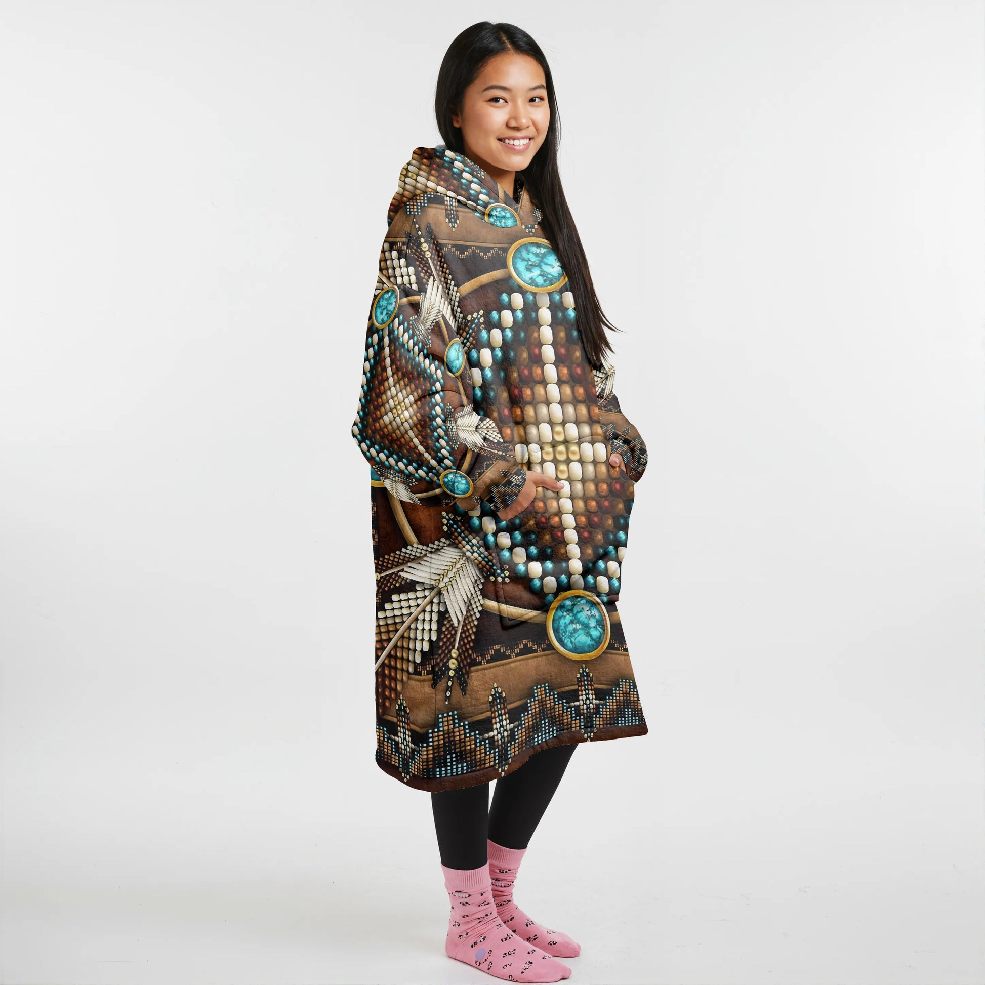 Side profile of a woman wearing a brown tribal blanket hoodie with turquoise medallion designs, hands in pockets, showing the hood and side panel