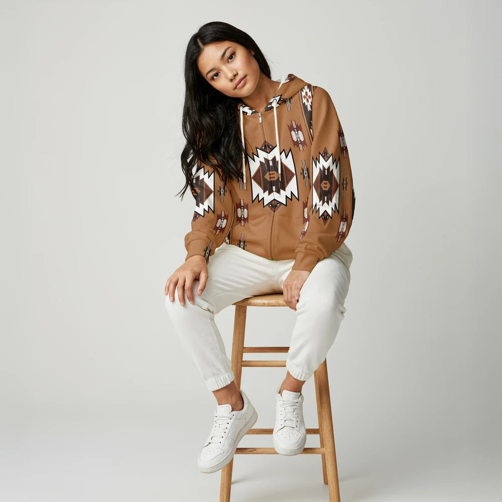Woman on a stool wearing a tan zip hoodie jacket featuring a black buffalo silhouette and tribal border trim