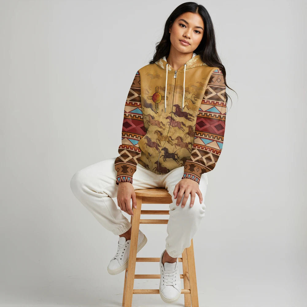 Model seated on a stool wearing a cream-colored zip hoodie jacket with turquoise and brown southwestern geometric pattern