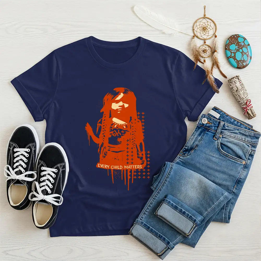 Navy blue Native America tee displaying symbolic Indigenous child graphic and message, accompanied by casual footwear and jeans.