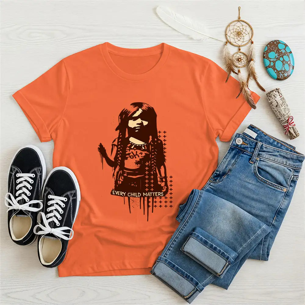 Orange unisex t-shirt with bold Indigenous child print and "Every Child Matters" text, styled with denim pants and casual shoes.