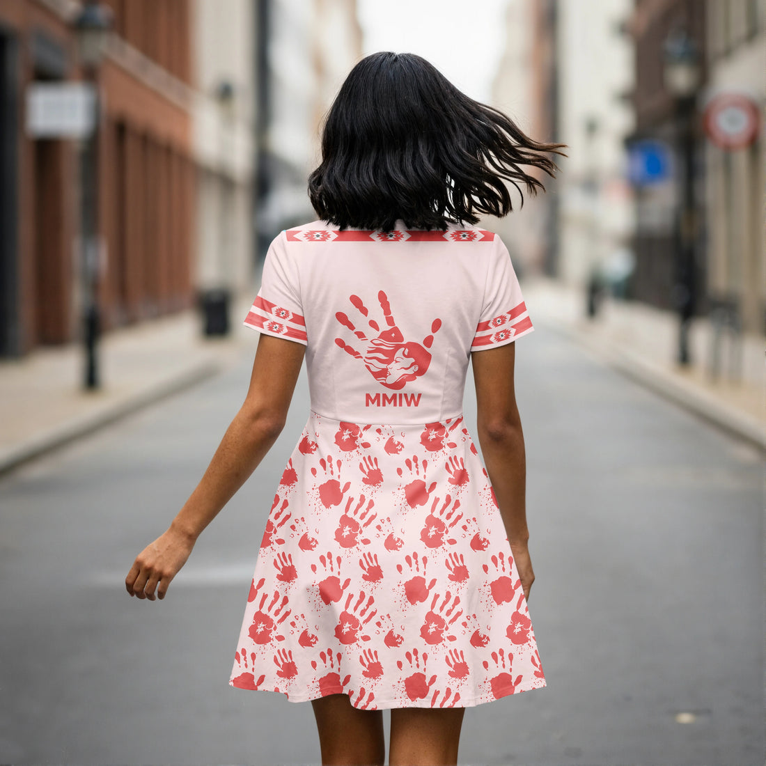 Woman wearing light pink V-neck skater dress with red handprints and tribal accents.