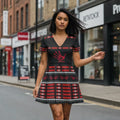 Woman wearing a V-neck dress with crimson handprint and tribal geometric patterns, walking on a city street, front view