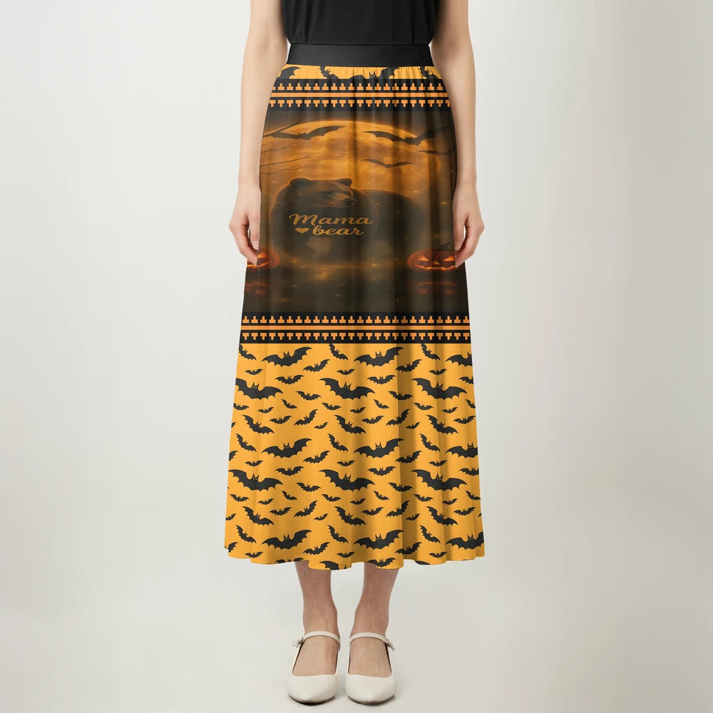 Full-length image of a woman wearing a black and orange maxi skirt. The top portion of the skirt features a "Mama Bear" graphic with a bear silhouette, moon, bats, and pumpkins against an orange sky, while the lower portion has an all-over black bat pattern on an orange background.