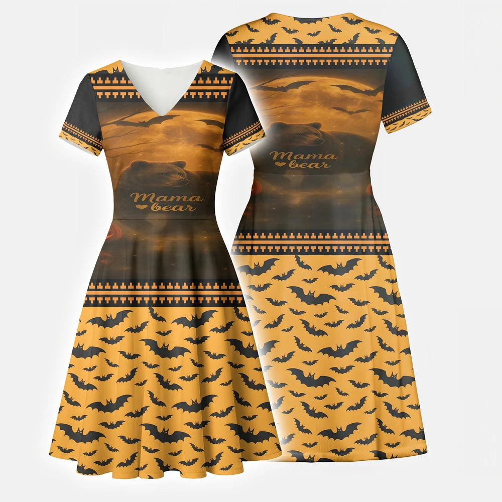 Front view of a black and orange V-neck A-line dress with short sleeves. The top half features a "Mama Bear" graphic with a bear silhouette, moon, bats, and pumpkins, while the skirt has an all-over black bat pattern on an orange background.