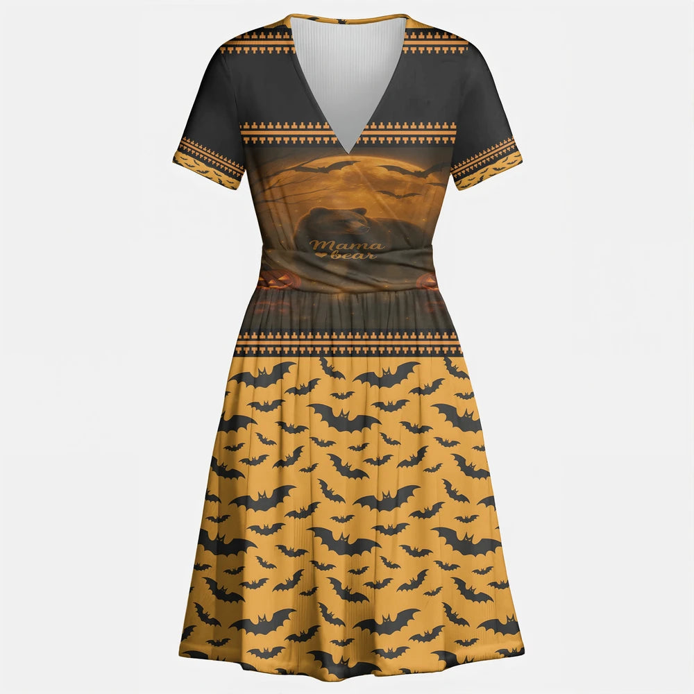 Front view of a black and orange V-neck A-line dress with short sleeves. The top half features a "Mama Bear" graphic with a bear silhouette, moon, bats, and pumpkins, while the skirt has an all-over black bat pattern on an orange background.
