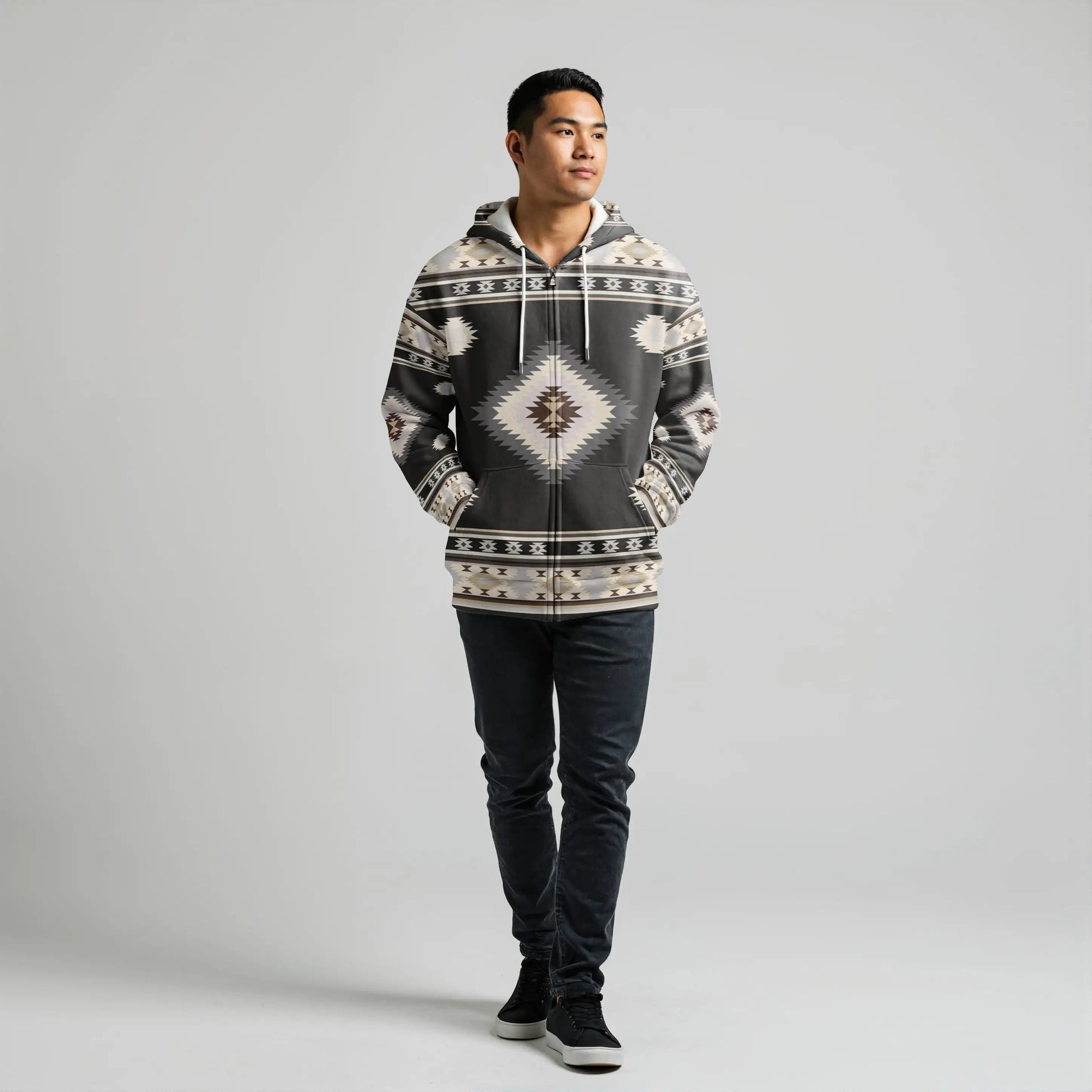 Front-on shot of a male model wearing a black and cream geometric tribal-patterned hooded wearable blanket, hands casually in the kangaroo pocket