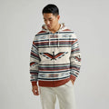 Male model wearing a cream and brown Native-American–inspired blanket hoodie with traditional stripe motifs, shown front view