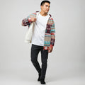 Male model wearing a multicolor Native-American–inspired zip-up jacket over a white tee, demonstrating the inside fleece lining against a neutral studio background