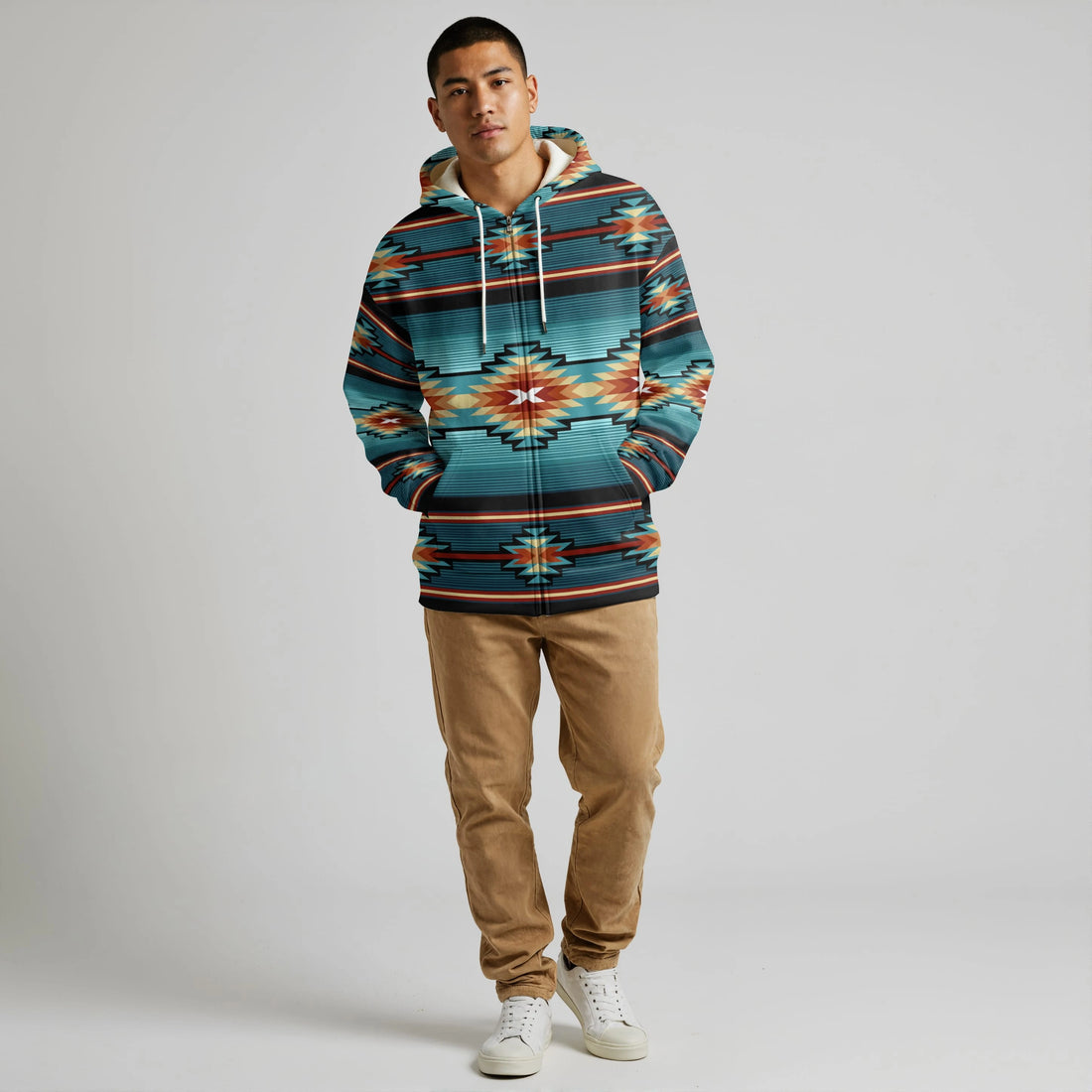 Front view of a male model in a teal Southwestern tribal hooded wearable blanket jacket with kangaroo pocket and geometric motifs