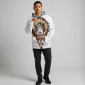 Front view of a male model in a white Native-American–inspired hoodie printed with a dreamcatcher medallion, hood up and hand adjusting the drawcord