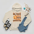 Beige hoodie featuring Native American graphic with chief headgear and the slogan 'Oh Sure Now You’re Against Immigration.'