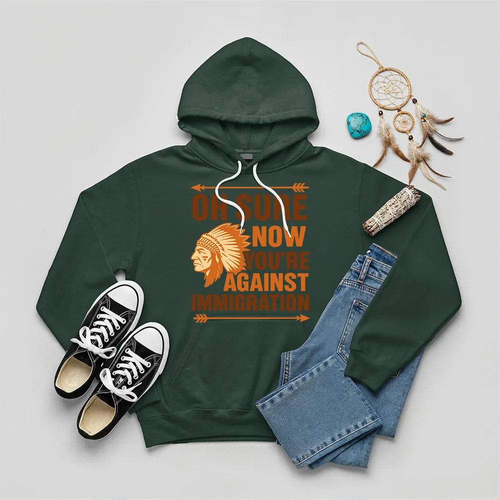 Green hoodie featuring Native American graphic with chief headgear and the slogan 'Oh Sure Now You’re Against Immigration.'