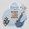 Light blue hoodie featuring Native American graphic with chief headgear and the slogan 'Oh Sure Now You’re Against Immigration.'
