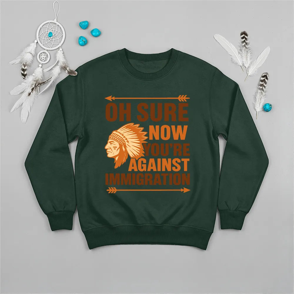 Native America graphic green sweatshirt with traditional chief headgear and 'Oh Sure Now You’re Against Immigration' text."