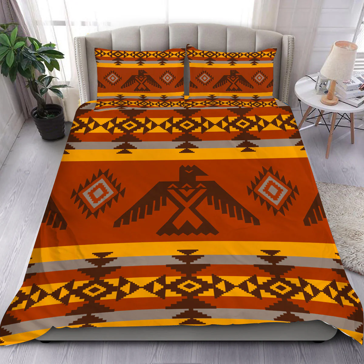 Bedding set featuring Native American inspired geometric patterns in warm orange, brown, yellow, and grey tones, shown on a made bed.