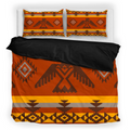 Bedding set with Native American inspired geometric pattern on the front and solid black reverse, displayed on a bed with matching pillowcases.
