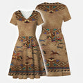 Front view of a women's V-neck wrap dress in a rich tan-brown color, adorned with a detailed Native American inspired print depicting warriors riding horses, other running horses, and intricate geometric tribal designs.
