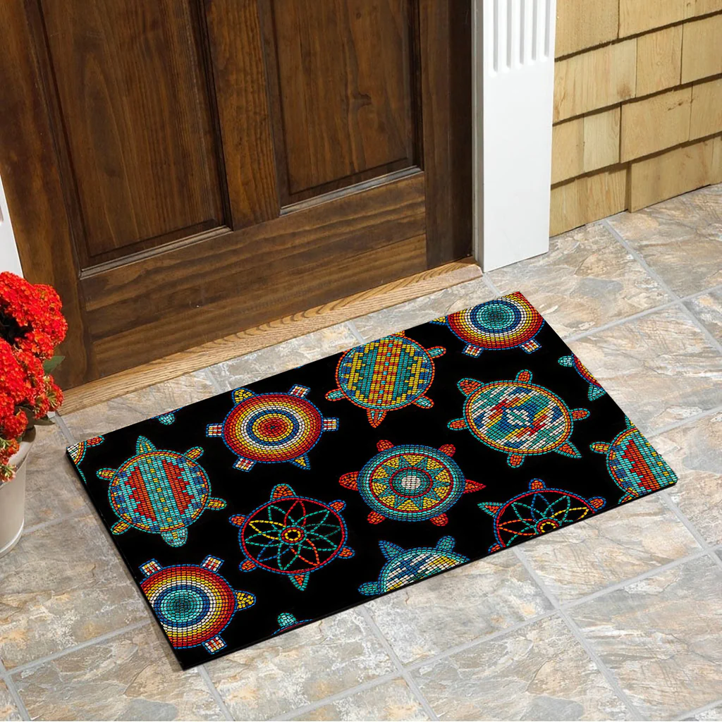 Outdoor doormat with vibrant Native American turtle patterns in bright colors on a black background, placed in front of a wooden door.