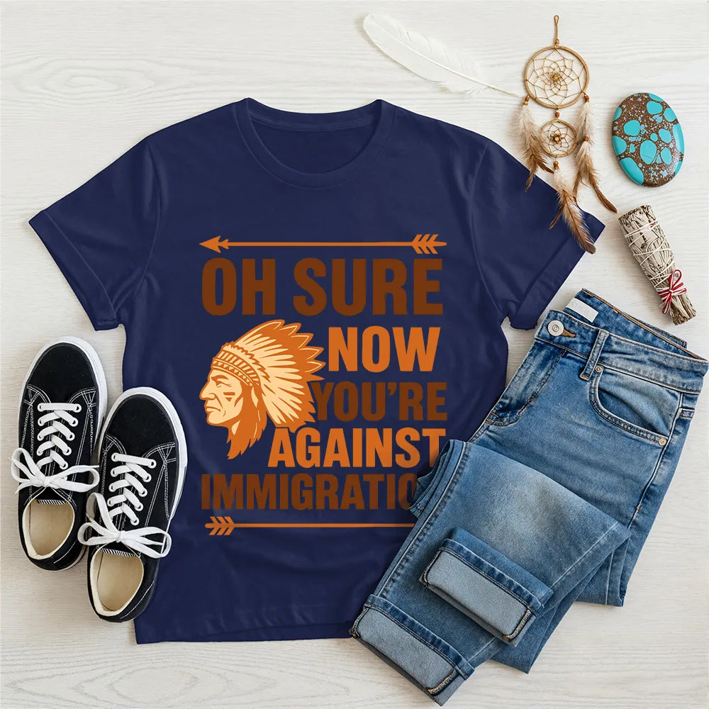 Navy t‑shirt featuring brown chief headdress graphic and text “Oh Sure Now Youre Against Immigration.”