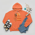 Orange hoodie with Indigenous‑style dreamcatcher and ‘It Speaks’ quote graphic