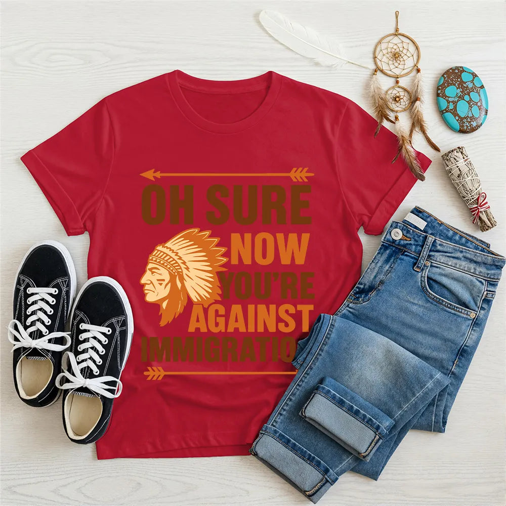 Forest green t‑shirt featuring brown chief headdress graphic and text “Oh Sure Now Youre Against Immigration.”