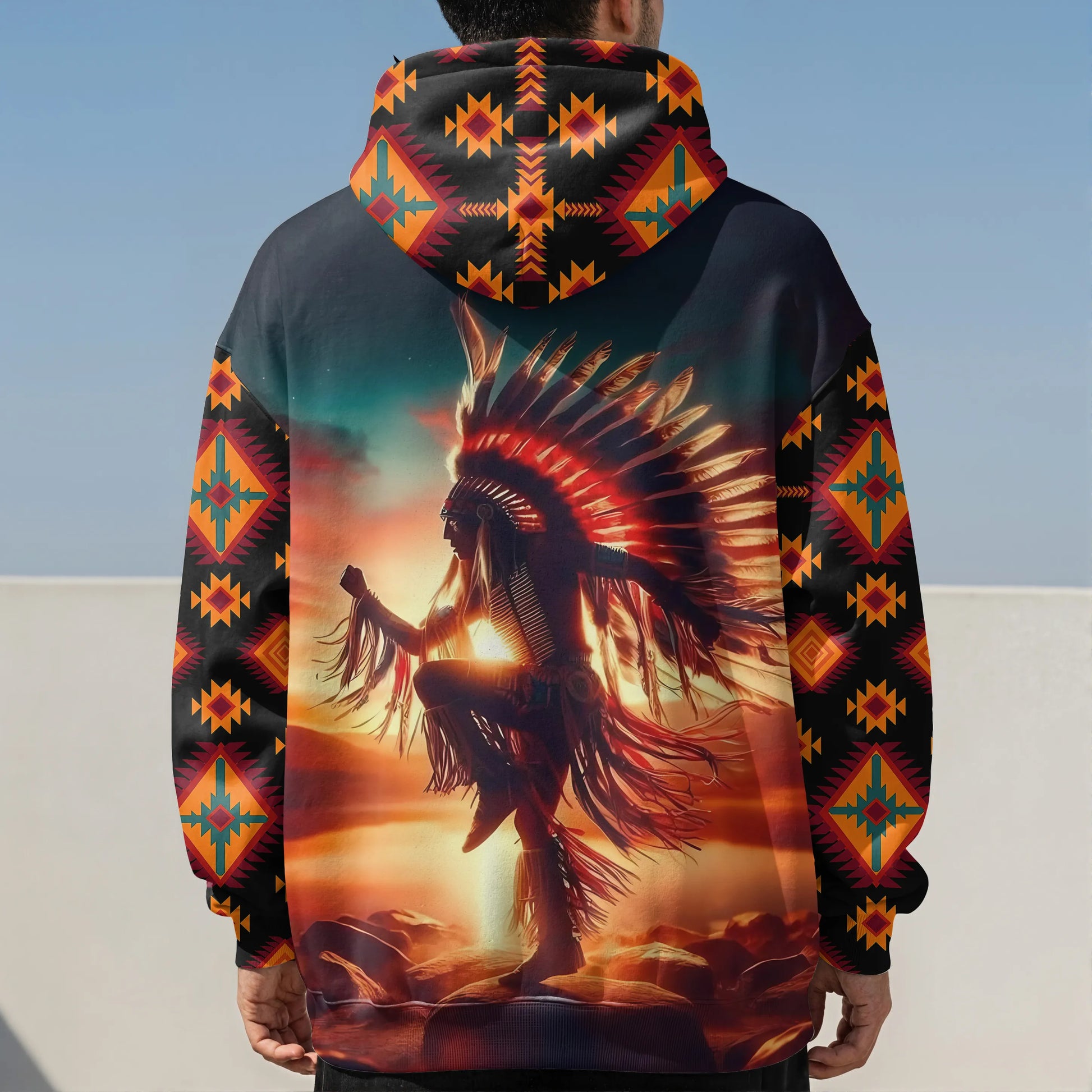 Back view of a hoodie showcasing a detailed print of a Native American dancer in a feathered headdress, silhouetted against a glowing sunset with tribal motifs on the sleeves and hood.