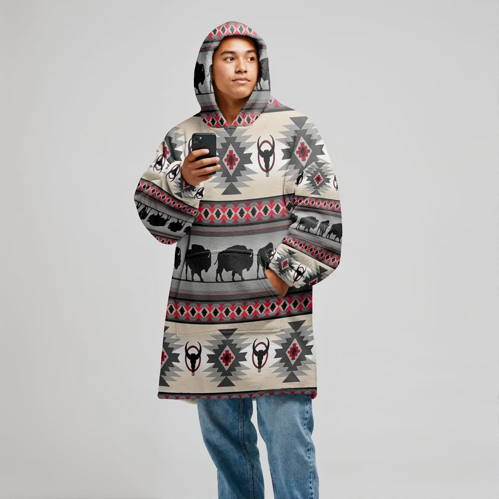 Model in a grey snug-up hoodie printed with red and black diamond tribal patterns, hood up and hands tucked in pouch pocket, photographed on white background