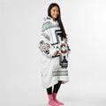 Side view of a person in a white wearable blanket hoodie featuring black buffalo prints and tribal accents, perfect for lounging or outdoor chill