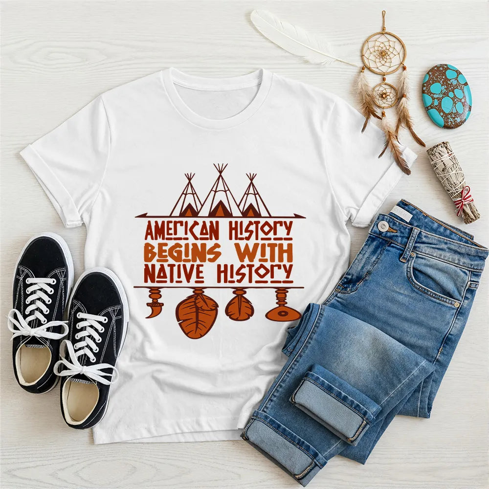 White t-shirt displaying brown teepee and feather totem graphic with quote “American History Begins with Native History