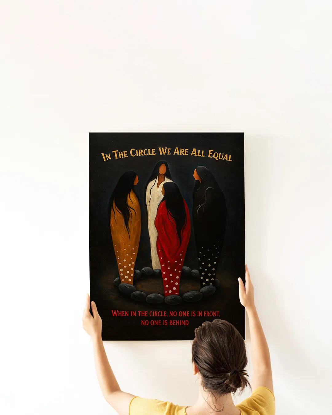 Lifestyle shot of a woman hanging the “In The Circle We Are All Equal” canvas print.