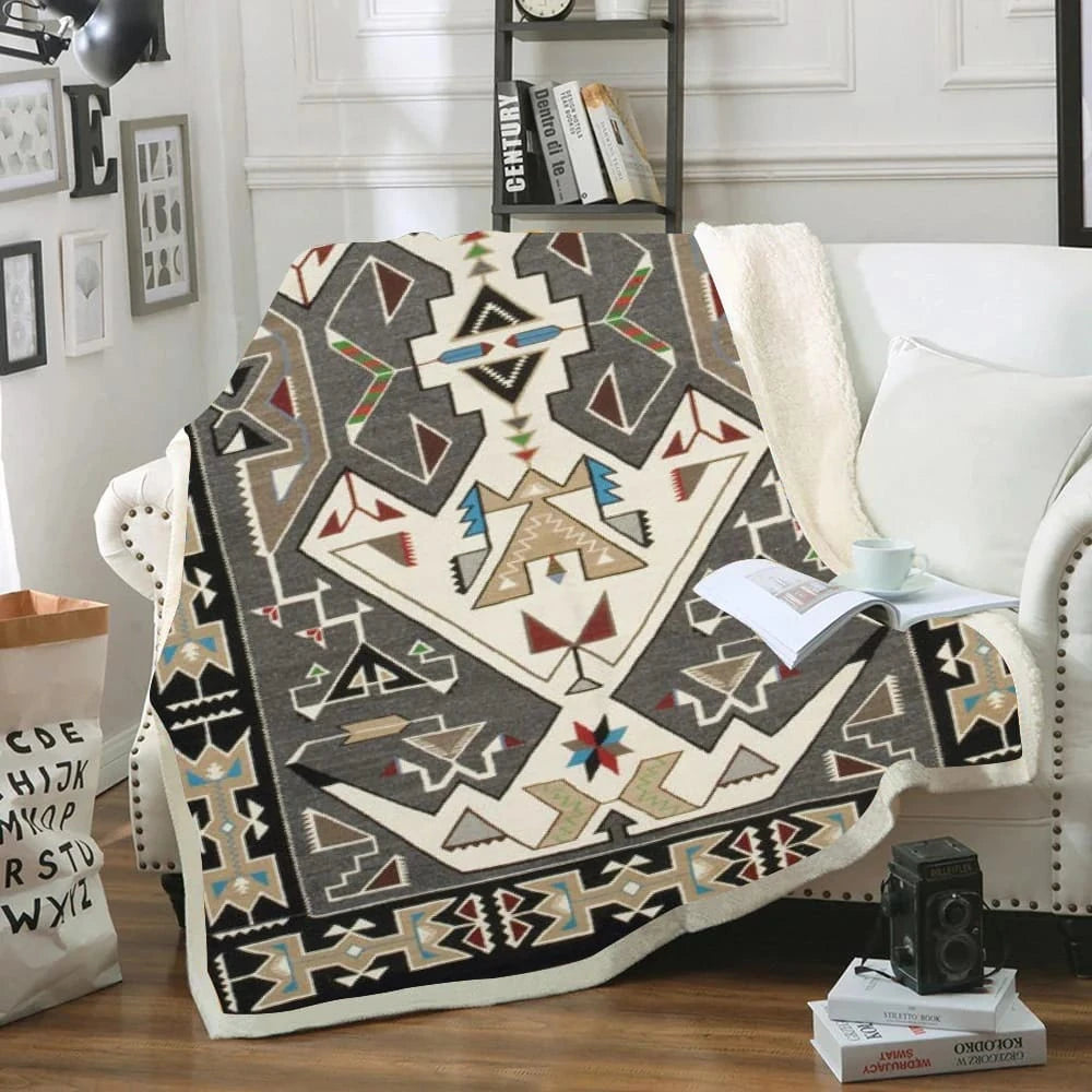 Great Basin Native American tribal pattern sherpa blanket draped over a white sofa with traditional geometric designs in earth tones