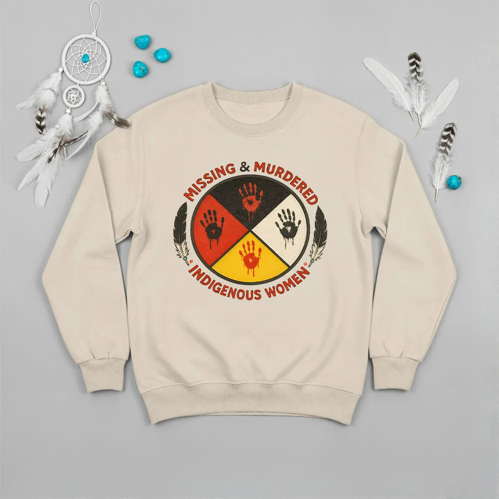 A beige sweatshirt with the "Missing & Murdered Indigenous Women" graphic, laid flat with relevant accessories.