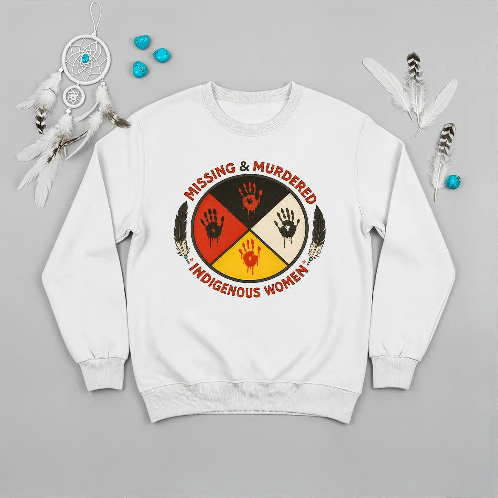A white sweatshirt displaying the MMIW awareness graphic with a red handprint, feathers, and text, laid flat.