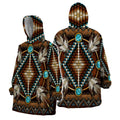 Front and back views of a snug hoodie featuring intricate Native American beadwork design with turquoise stones, white arrow motifs, and multicolored beads on a rich brown background.