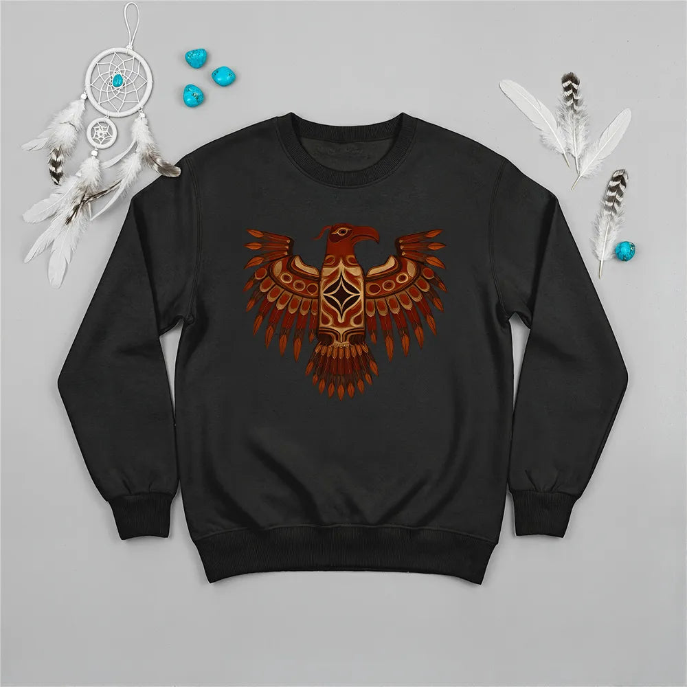 A black crewneck sweatshirt with a vibrant Native American Thunderbird graphic, displayed with indigenous-inspired accessories.