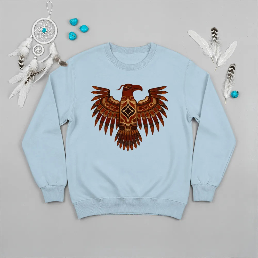 A light blue crewneck sweatshirt with a central Native American Thunderbird artwork, presented with decorative feathers and sage.