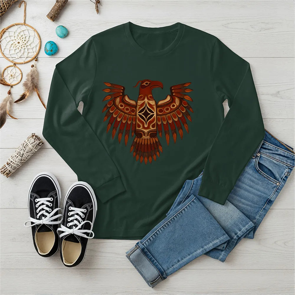 A forest green long-sleeve t-shirt with an indigenous-inspired Thunderbird motif, displayed with casual jeans and accessories.
