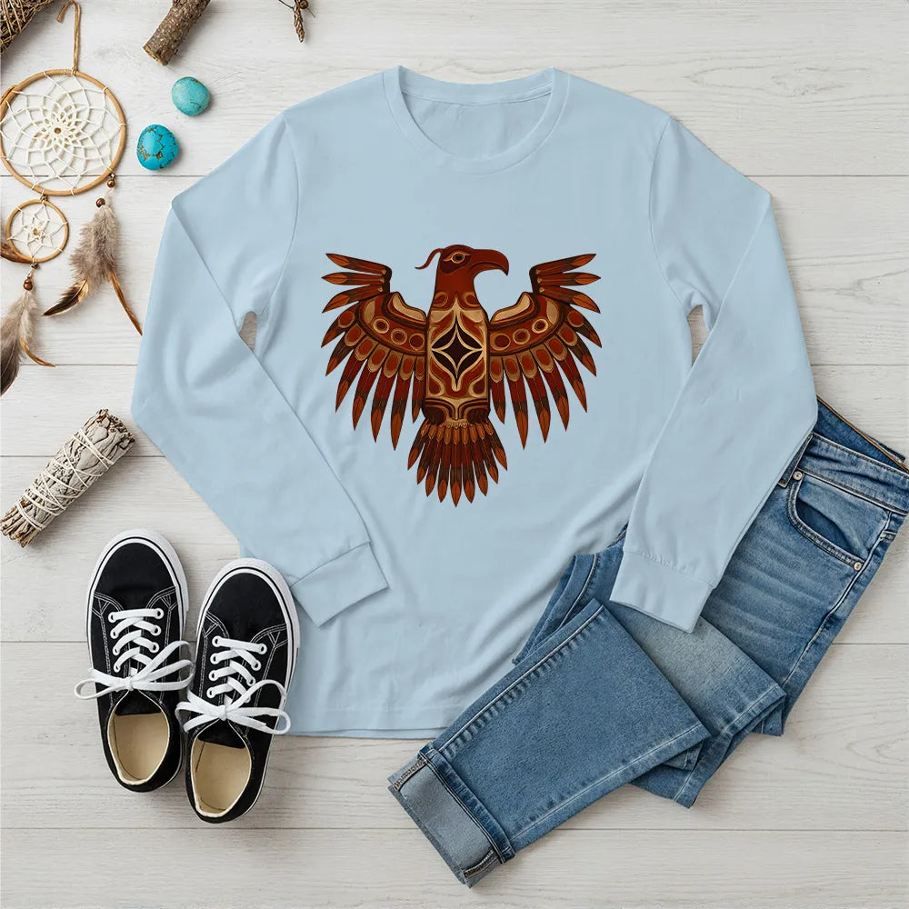 A light blue long-sleeve t-shirt with a central Native American Thunderbird artwork, presented with a casual outfit.
