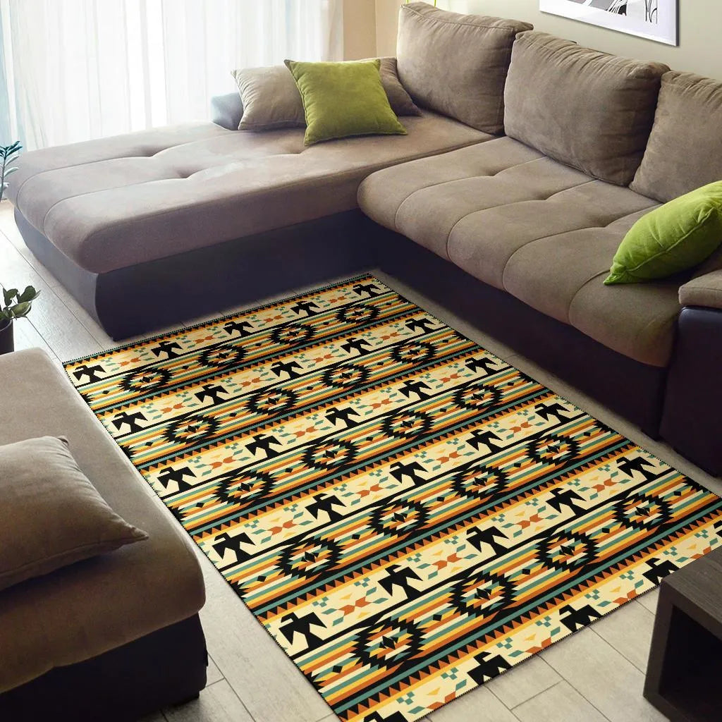 Living room with sectional sofa showing a Native American Thunderbird pattern rug featuring black thunderbird silhouettes and geometric motifs in orange, yellow, and teal on a cream background.