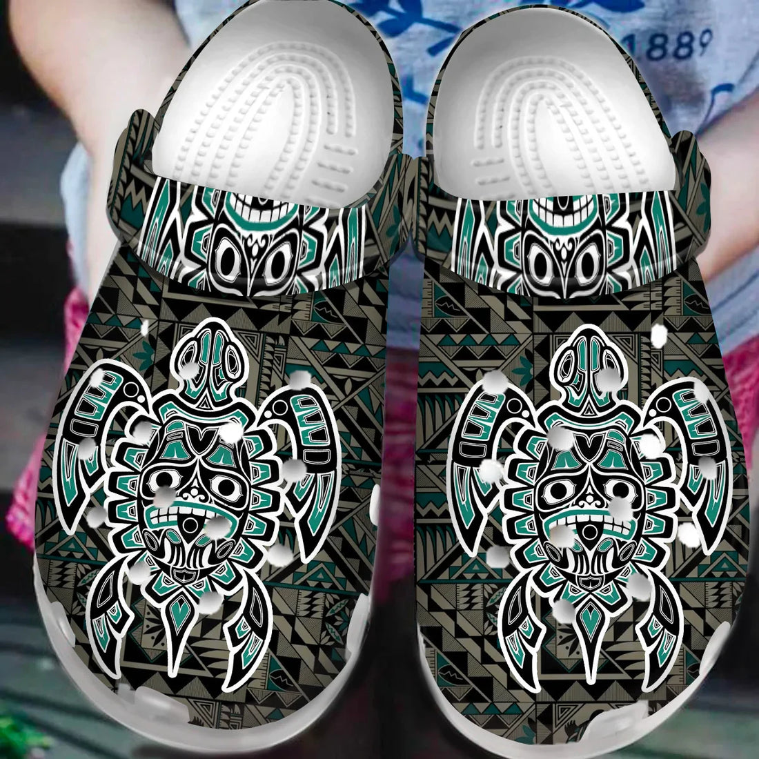 Pair of Native American tribal pattern Crocs sandals on natural outdoor background.