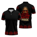 Black polo shirt with red geometric border along hem, sleeves, and shoulders; back features an elder’s weathered face above bold red and gold text reading “Still Here Still Strong Native Pride.”