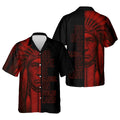 Black short‑sleeve camp shirt with red geometric patterns on the shoulders and hem; back art shows a warrior portrait with the phrase “No One Is Illegal on Stolen Land.”