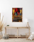 “INDIGENOUS” canvas print displayed above a wooden console, showcasing horse riders at sunset and campfire scenes within a tribal border.