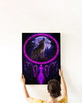 A woman’s hands hanging a framed canvas print featuring a purple wolf howling inside a dreamcatcher ring against a moonlit forest backdrop.