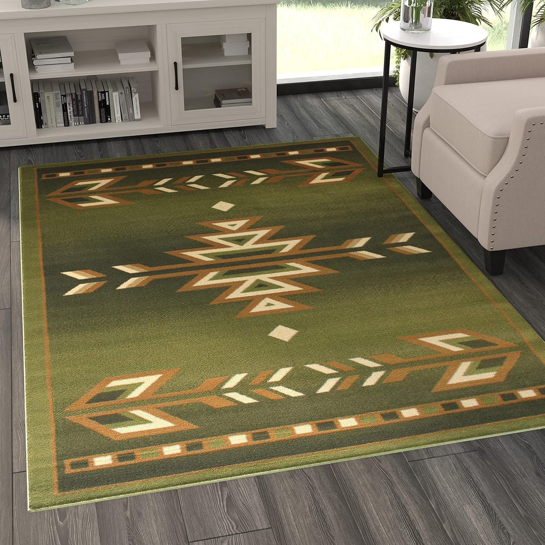 Close-up view of the front edge of the green tribal rug, highlighting the woven texture and ochre-and-cream triangular arrowhead pattern on an olive-green background.