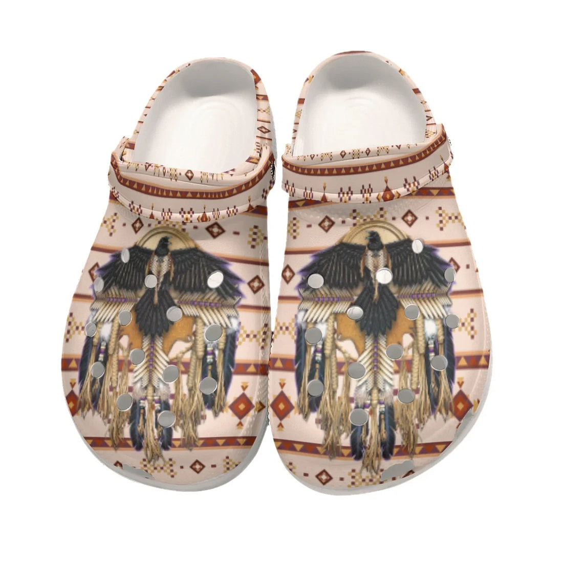 Top-down shot of cream-colored clog mules with crow and dreamcatcher motif and heel strap positioned forward on a white surface.