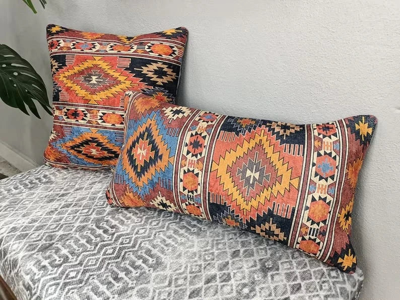 Close-up of a square Southwestern Aztec pattern throw pillow in rust, navy, and gold hues with a concealed zipper.
