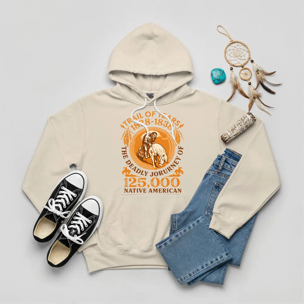 A beige hoodie with the "Trail of Tears" historical graphic, presented with Native American symbols like a dreamcatcher and sage.